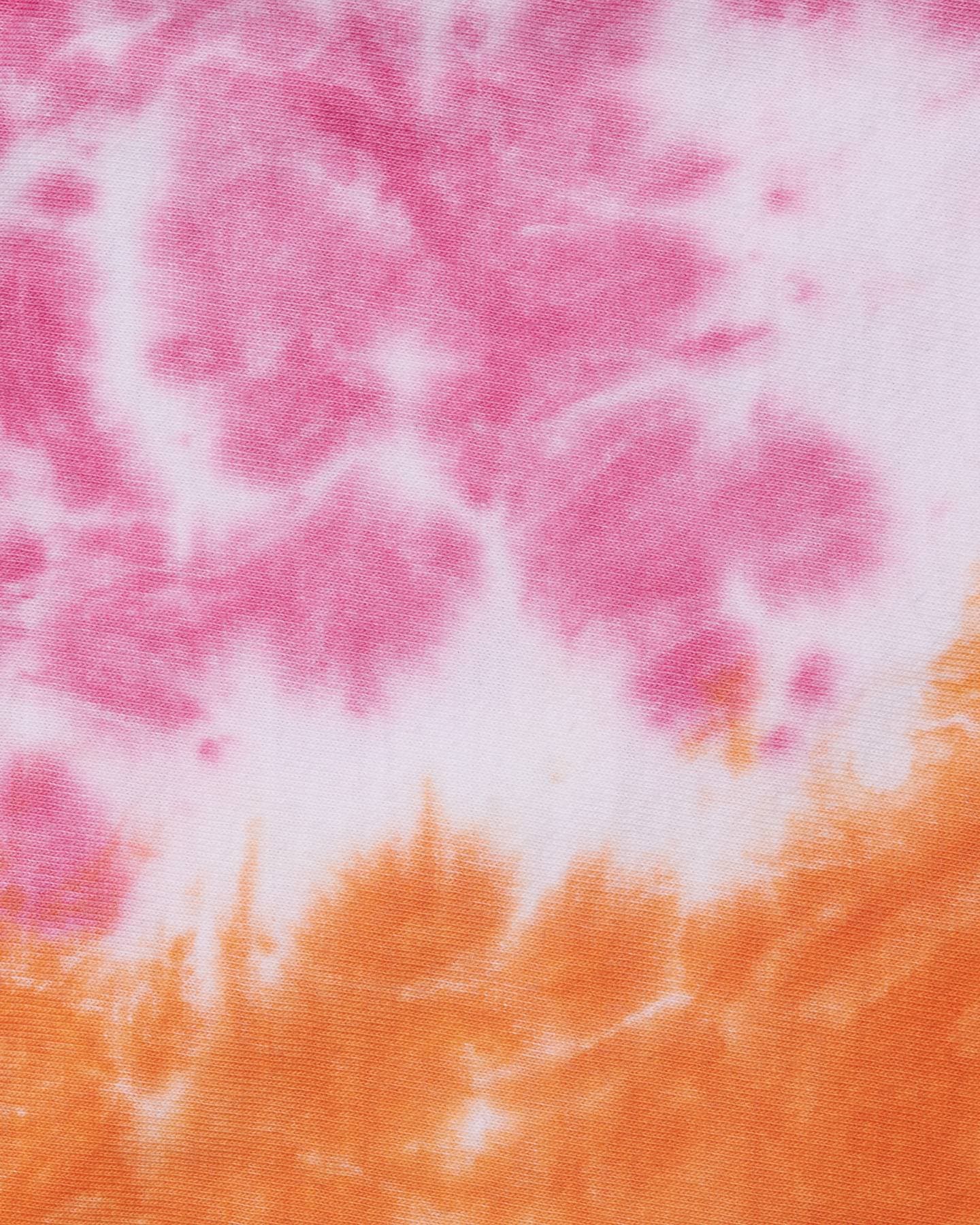 Close-up of the knit fabric of the tie-dye T-shirt, dyed pink and white above and orange below.