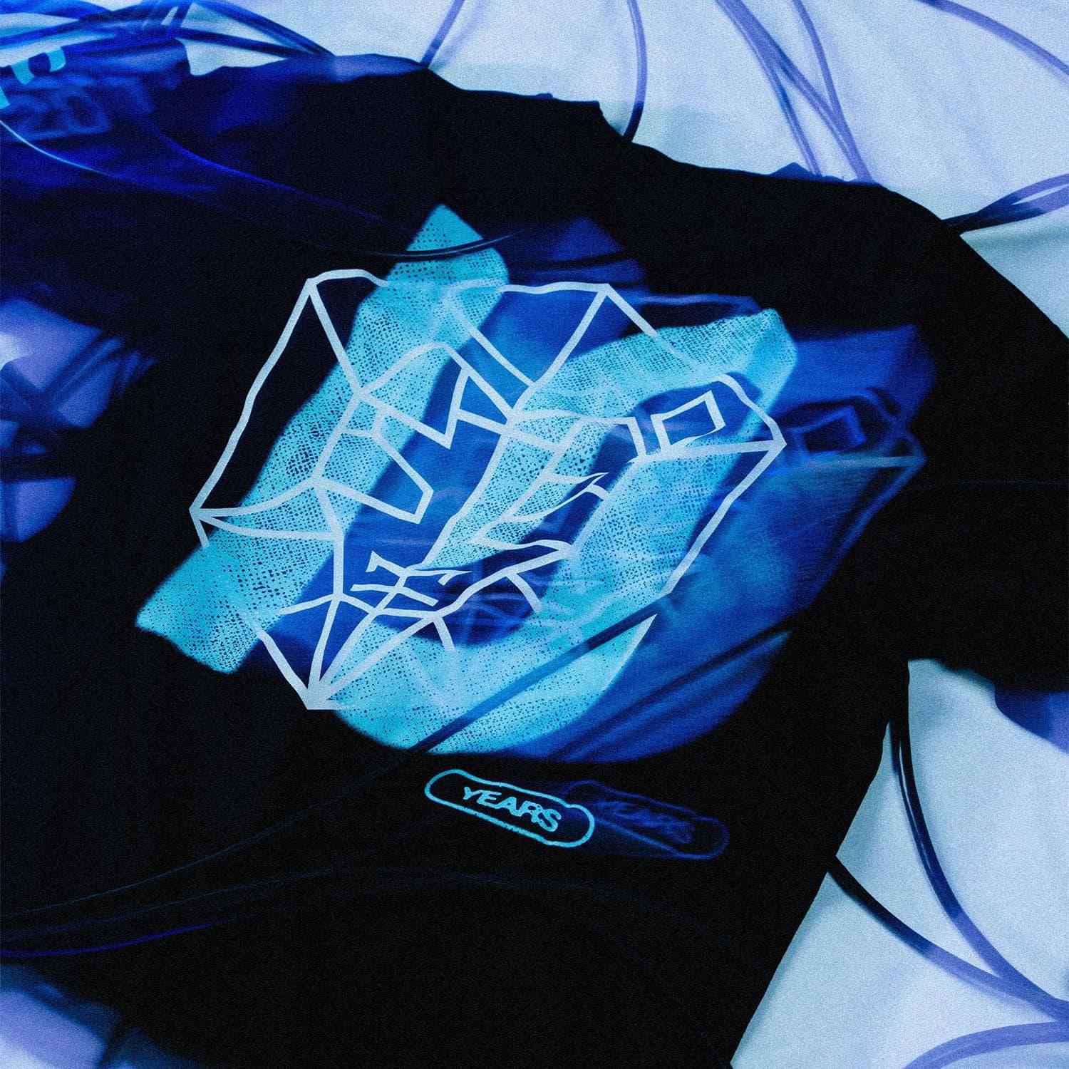 Close-up of a black STMPD RCRDS 10 Years longsleeve with a translucent print, in blue light.